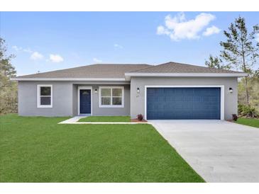 Charming single-story home showcasing a well-manicured lawn and a blue two-car garage, adding curb appeal at 42 Fisher Way Trak, Ocala, FL 34473