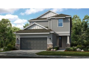Two-story house with gray siding, dark gray garage door, and stone accents at 5702 Gingham Dr, Kissimmee, FL 34758