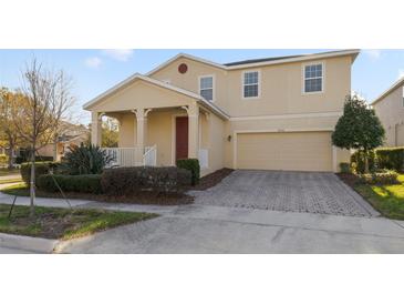 Two-story house with a red door, two-car garage, and landscaped yard at 14502 Bahama Swallow Blvd, Winter Garden, FL 34787