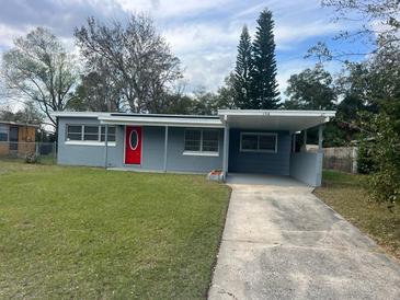 Charming single-story home features a red front door, carport, and well-maintained lawn at 158 Country Club Cir, Sanford, FL 32771