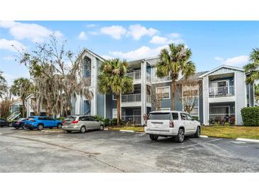 Three-story condo with a large parking lot, balconies, and palm trees at 2521 Grassy Point Dr # 309, Lake Mary, FL 32746