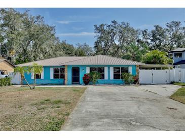 Charming turquoise ranch-style home with a metal roof, stone accents, and a spacious driveway at 27622 Lois Dr, Tavares, FL 32778