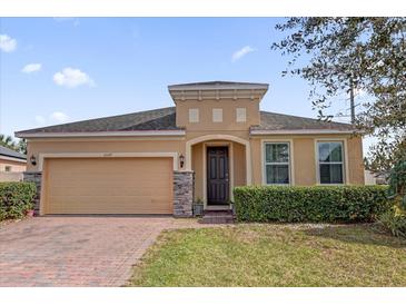 Charming single-story home with brick driveway, two-car garage, arched entryway, and manicured landscaping at 3337 Reedy Glen Dr, Kissimmee, FL 34758