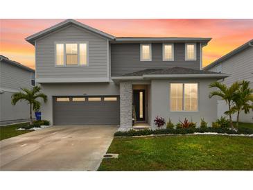 Two-story home with a gray and white color scheme, well-manicured lawn, and attached two-car garage at 4104 Southern Vista Loop, St Cloud, FL 34772