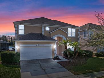 Two-story house with tan exterior, white garage door, and palm trees in the front yard at 4700 Golden Beach Ct, Kissimmee, FL 34746