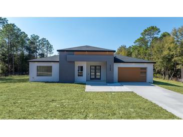 Contemporary single-story home featuring a modern gray and white facade and well-manicured lawn at 5544 Sw 136Th Ave, Ocala, FL 34481