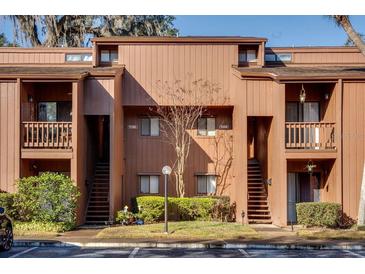 A two-story condo featuring a traditional design with balconies, brown siding, and a well-maintained lawn at 970 E Michigan St # B, Orlando, FL 32806