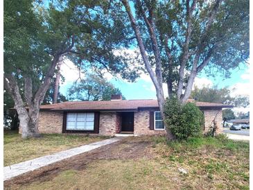 Charming brick ranch-style home featuring a well-maintained lawn and mature trees at 2079 Longfellow Ct, Orlando, FL 32818