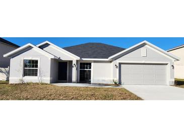 Newly constructed one-story home with gray siding, two-car garage, and well-manicured lawn at 411 Caribbean Ct, Kissimmee, FL 34759