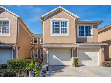 Inviting townhome featuring an attached garage and mature landscaping at 6443 Axeitos Ter # 105, Orlando, FL 32835