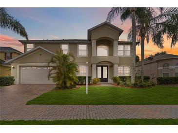 Two-story home showcasing manicured lawn and lush tropical landscaping, complemented by a two car garage at 10068 Chardonnay Dr, Orlando, FL 32832