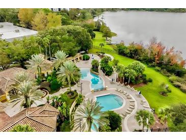 Beautiful aerial view of a resort-style pool, deck with lounge chairs, and lush landscaping with lake in the background at 1616 Legacy Park Dr # 1616, Maitland, FL 32751