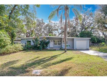 Charming single-story home with a manicured lawn and lush landscaping, including a central palm tree at 6408 Ridge Ter, Orlando, FL 32810