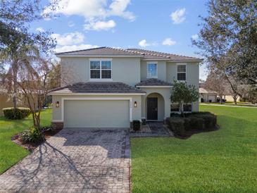 Charming two-story home featuring a paver driveway, tile roof, and lush landscaping at 9026 Paolos Pl, Kissimmee, FL 34747