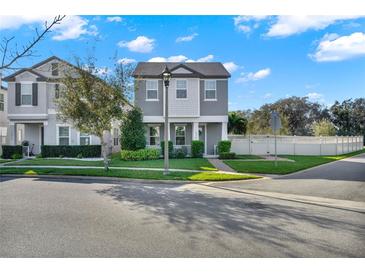 Charming two-story home with a manicured lawn and elegant gray exterior, and lush landscaping at 10319 Austrina Oak Loop, Winter Garden, FL 34787