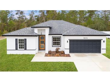 Charming single-story home with modern white exterior, gray roof and a dark gray two car garage at 16074 Sw 49Th Court Rd, Ocala, FL 34473