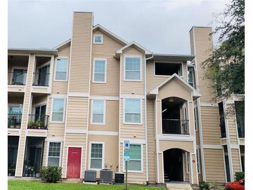 Three-story condo with a red front door, beige siding, balconies, and covered entry at 2000 Erving Cir # 201, Ocoee, FL 34761