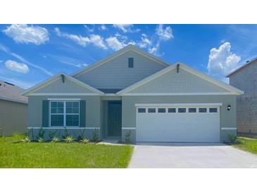 Charming single-Gathering home featuring a two-car garage, manicured lawn, and craftsman-style architecture at 2141 Pigeon Plum Dr, Haines City, FL 33844