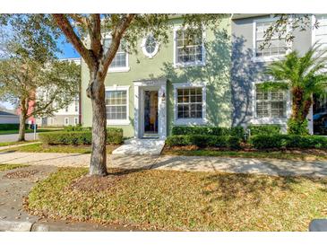 Two-story townhome featuring an oval window accent, lush landscaping, and a tree-lined walkway at 3668 Peppervine Dr, Orlando, FL 32828