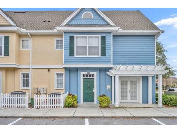 Charming two-story townhome with blue siding, a green door, and a white pergola over the entrance at 4004 San Gallo Dr # 107, Kissimmee, FL 34741