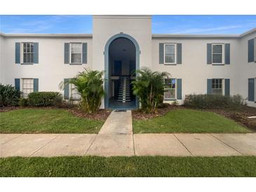 Exterior view of building with blue shutters, arched entry, small trees, and sidewalk at 1030 Plantation Dr # C6, Kissimmee, FL 34741