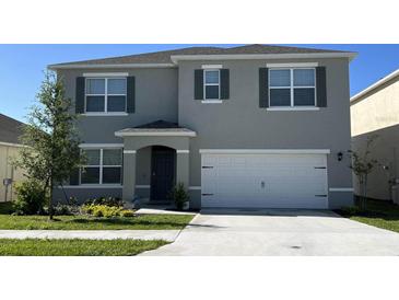 Two-story home featuring a two-car garage, well-manicured lawn, and complementary landscaping at 1336 Hanoverian Dr, Lake Alfred, FL 33850