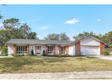 Charming single story home with brick accents, tidy landscaping, and an attached two-car garage at 203 E Sweetwater Creek Dr, Longwood, FL 32779