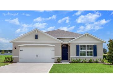 Charming single-story home featuring a two-car garage, blue shutters, manicured lawn, and a welcoming front entrance at 2117 Pigeon Plum Dr, Haines City, FL 33844