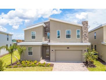 Modern two-story home featuring stone accents, a two-car garage, and a well-maintained front lawn at 351 Ocean Course Ave, Davenport, FL 33896