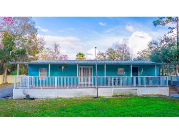 Charming turquoise home with a covered porch and white railings, nestled in a lush, green yard at 630 Carpenter Rd, Orlando, FL 32833