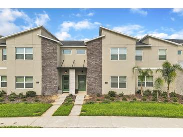 Modern townhome exterior featuring stone accents, green doors, and well-manicured landscaping at 994 Splash Shot Pl, Davenport, FL 33896