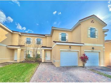 Inviting townhome exterior with a red brick driveway, two garages, and terracotta roof tiles at 1183 Chervil Dr, Poinciana, FL 34759