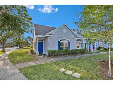 Charming home with a blue front door and shuttered windows, nestled amongst mature trees at 2207 Island Walk Dr, Orlando, FL 32824