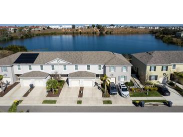 An aerial view of townhomes featuring solar panels and a serene lake backdrop at 360 Arbor Lakes Dr, Davenport, FL 33896