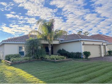 Landscaped single-story home featuring a well-manicured lawn, tropical plants, and tile roof at 4119 Bella Isle Cir, Kissimmee, FL 34746