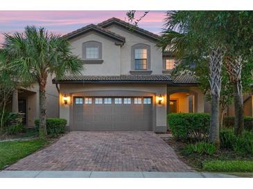 Beautiful home exterior featuring a brick driveway and attached garage, enhanced by mature palm trees and professional landscaping at 8920 Rhodes St, Kissimmee, FL 34747