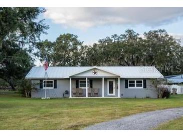 Charming single-story home featuring a metal roof, covered porch and American flag at 9919 Hickory Hollow Rd, Leesburg, FL 34788