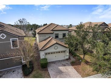 Two story home showcasing a tile roof, attached two car garage, and brick paver driveway at 1494 Moon Valley Dr, Davenport, FL 33896
