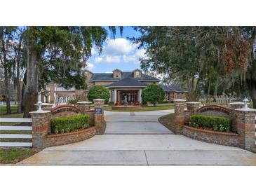 Beautiful estate home featuring brick entrance with landscaped garden, water feature, and manicured grounds under a blue sky at 1501 Lake Markham Rd, Sanford, FL 32771