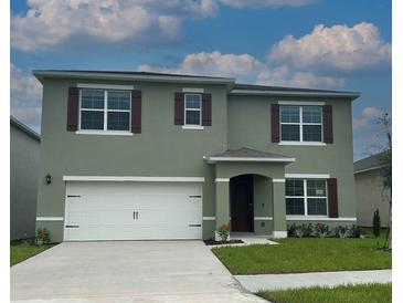 Two-story home with a white garage door, and shutters, with a well-maintained lawn at 2129 Pigeon Plum Dr, Haines City, FL 33844