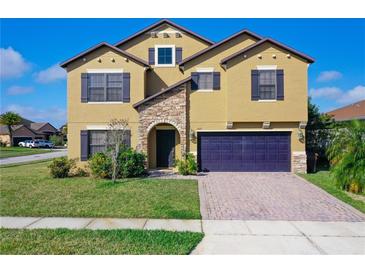 Two-story home with a tan exterior, stone entryway, well-kept lawn, and a two car garage at 1515 Angler Ave, Kissimmee, FL 34746