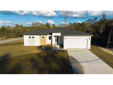 New construction home featuring a modern design, two-car garage and a well-manicured lawn at 15215 Sw 43Rd Ct, Ocala, FL 34473