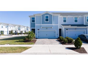 Charming light blue townhome with a brick-paved driveway and manicured landscaping at 2939 Sentence St, Kissimmee, FL 34746