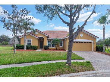 Charming single-story home with a red tile roof, manicured lawn, and mature landscaping under a blue sky at 4036 Bougainvillea Pl, Kissimmee, FL 34746