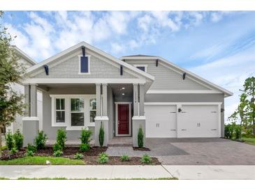 Charming single-story home featuring a red front door, a two-car garage, and meticulously landscaped front yard at 15491 Lebeau Loop, Winter Garden, FL 34787