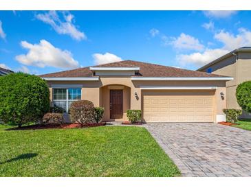 Charming single-story home with a well-manicured lawn, tan exterior and attached two car garage at 4605 Kalispell Rd, Kissimmee, FL 34758