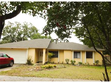 Charming single-story home with mature trees, a two-car garage, and tidy front yard landscaping at 4790 Point Look Out Rd, Orlando, FL 32808