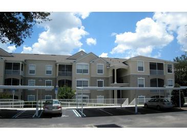 Exterior view of condo building, showcasing the covered parking, tan color, and second-story facade at 586 Brantley Terrace Way # 201, Altamonte Springs, FL 32714