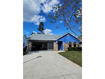 Charming single-story home featuring blue siding, brick accents, and a spacious driveway on a sunny day at 703 Pine Shores Cir, New Smyrna Beach, FL 32168