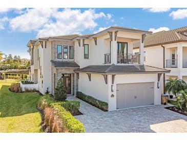 Beautiful two-story home featuring a stone facade, balcony, well-manicured lawn and two-car garage at 985 Jack Nicklaus Ct, Kissimmee, FL 34747